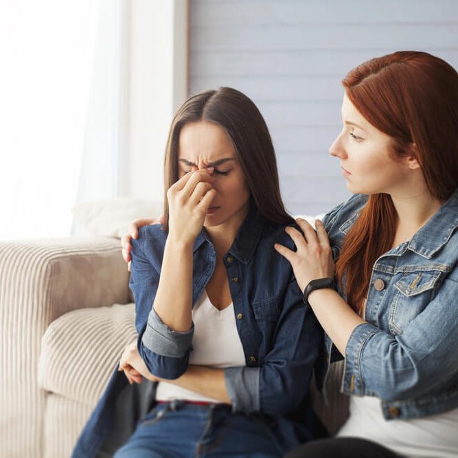 Grieving woman having to deal with family's deceased estate while friend is comforting her.